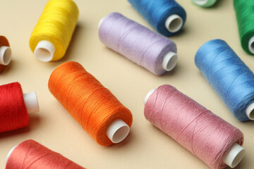 Fototapeta na wymiar Different colorful sewing threads on beige background