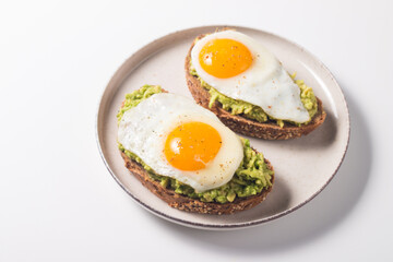 Avocado egg sandwich with a glass of water. Healthy light breakfast concept. Whole grain toasts with mashed avocado and fried eggs