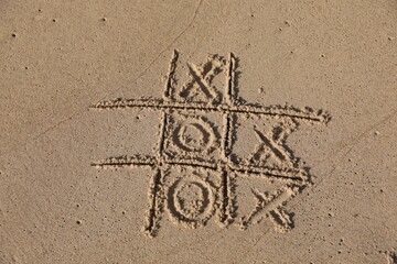 Tic tac toe game drawn on sandy beach, above view