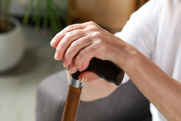 Obraz na płótnie Canvas Elderly woman with walking cane indoors, closeup. Home care service