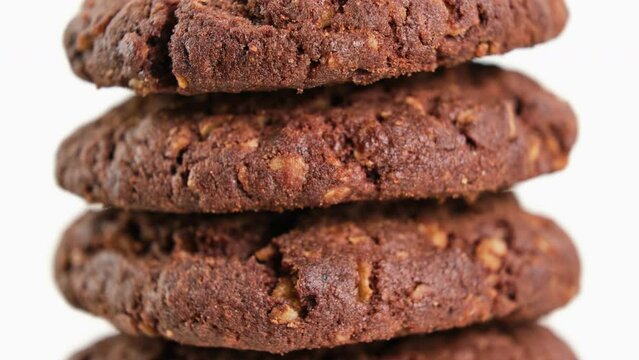 Stack of brown oatmeal cookies appearing on white background. American food concept. Fresh homemade cookies. Stop motion. Morning breakfast. Tasty bakery dessert. Close-up in 4K, UHD