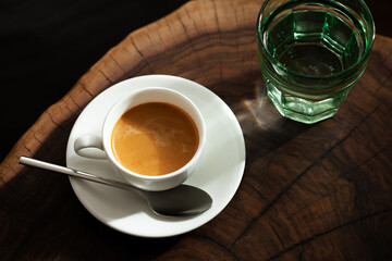 Espresso in a white cup served with a glass of water
