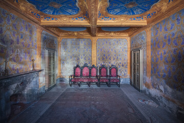 Fototapeta na wymiar Decayed room in palace storing antique chairs