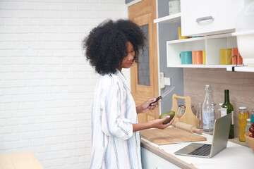 Shot of a A young black girl with afro hair woman preparing and eating fruit before making a smoothie.