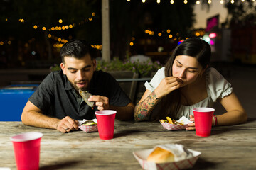 Beautiful couple eating delicious tacos at night