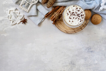 Latte spice coffee, warm pullover and Christmas decor on gray background.  Seasonal winter concept with hot drink, creative flat lay. View from above. Copy space.