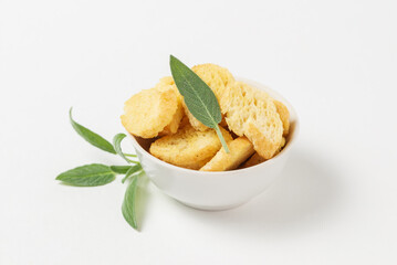 Bread croutons in white bowl complemented with green sage leaves isolated