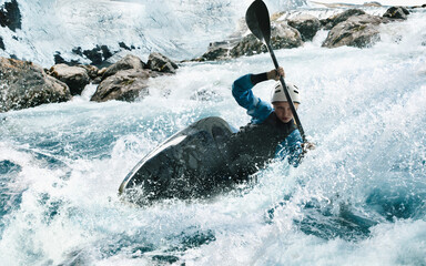 Woman in a kayak sails on a mountain river. Whitewater kayaking, extreme kayaking.