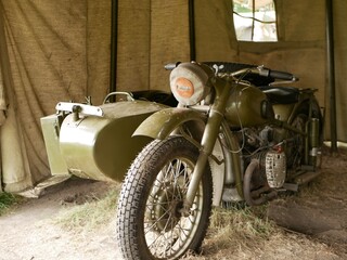 A military motorcycle with a sidecar under an awning. Military camouflage motor vehicles of the Second World War.