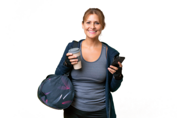 Middle-aged sport woman with sport bag over isolated background holding coffee to take away and a mobile