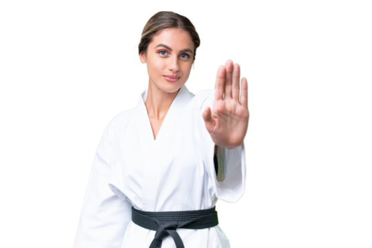 Young Uruguayan woman doing karate over isolated background making stop gesture