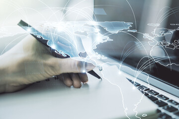 Double exposure of abstract digital world map with connections and hand writing in notepad on background with laptop, big data and blockchain concept