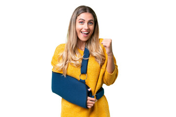 Young Uruguayan woman with broken arm and wearing a sling over isolated background celebrating a victory in winner position - obrazy, fototapety, plakaty