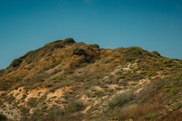 Fototapeta na wymiar Peak of a hill covered with rocks and grass on a clear day in Herzliya, Israel