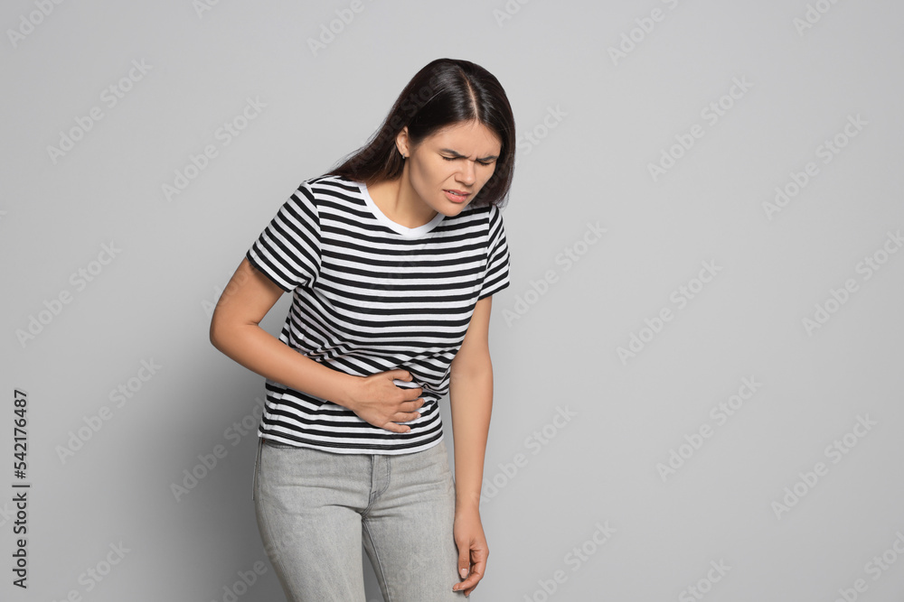 Sticker Young woman suffering from menstrual pain on grey background, space for text