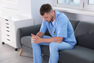 Exhausted doctor sitting on sofa in hospital