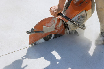 Working on concrete sidewalk using diamond blade saw to cuts concrete