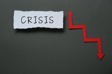 Paper piece with word Crisis and descending red arrow on black background, flat lay. Space for text