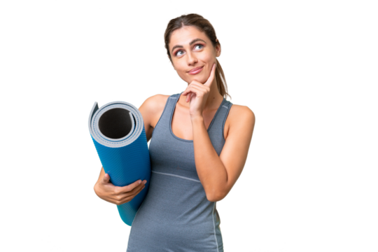 Pretty Young Uruguayan sport woman going to yoga classes while holding a mat over isolated background thinking an idea while looking up