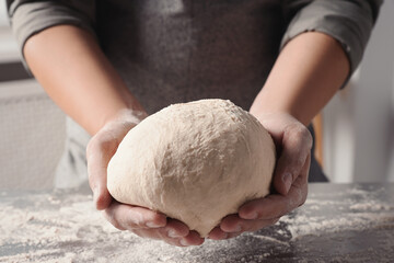 Man kneading dough at table in kitchen, closeup