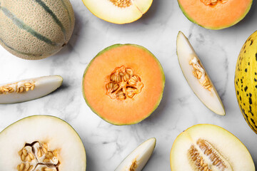 Tasty colorful ripe melons on white marble table, flat lay - obrazy, fototapety, plakaty