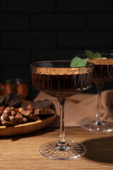 Dessert bowls of delicious hot chocolate and ingredients on wooden table, closeup
