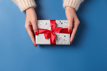 Christmas present. Woman with gift box on blue background, top view