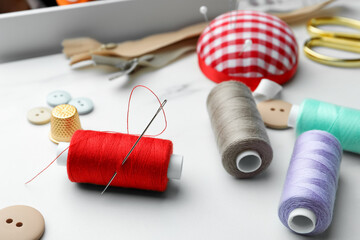 Threads and other sewing supplies on white marble table