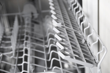 Open clean empty dishwasher in kitchen, closeup