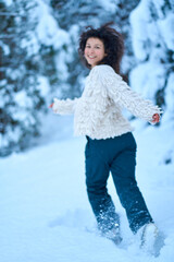 The woman having fun walking in snow covered winter forest