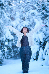 Fototapeta na wymiar A woman happily playing with snow in a snow-covered winter forest