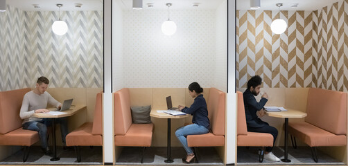 Workflow in modern co-working office space of three diverse Indian and Caucasian businesspeople...