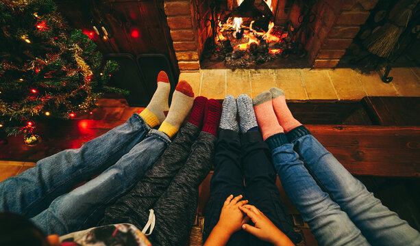 Happy Family Wearing Warm Socks In Front Of Cozy Fireplace During Christmas Time - Focus On Socks