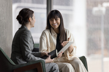 Meeting in office of two smiling businesswomen with digital tablet, appointment of client and sales...