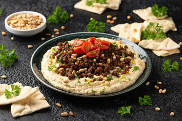 Hummus with spiced ground beef, olive oil, tomatoes and toasted pine nuts