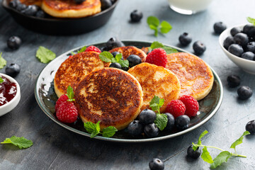 Cottage cheese pancakes served with blueberries, raspberries, strawberry jam and mint leaves, healthy vegetarian protein breakfast
