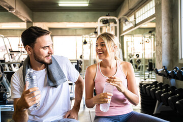 Fototapeta na wymiar Happy couple drinkking water after exercise in sport fitness gym