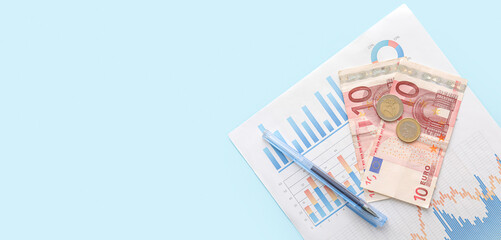 Euro banknotes with coins, pen and diagrams on blue background with space for text. Exchange rate concept