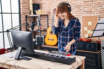 Young woman musician playing piano keyboard at music studio