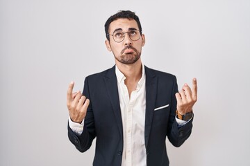 Handsome business hispanic man standing over white background pointing up looking sad and upset, indicating direction with fingers, unhappy and depressed.