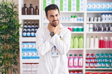 Fototapeta premium Handsome hispanic man working at pharmacy drugstore shouting suffocate because painful strangle. health problem. asphyxiate and suicide concept.