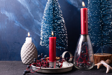 Re and blue Christmas decorations. Red burning candle in rustic holder, wid blue berries and blue...