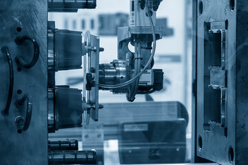 The robotic arm gripping the plastic cup from the injection machine.
