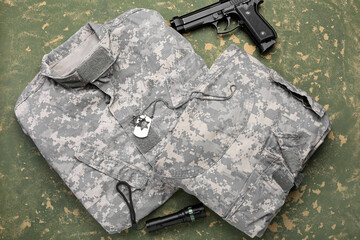 Military uniform, gun, flashlight and tag on color background