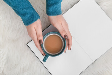 Woman with book and cup of coffee, closeup