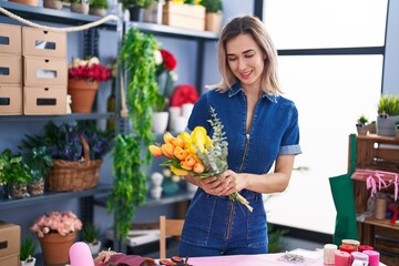Young woman florist holding bouquet of flowers at florist