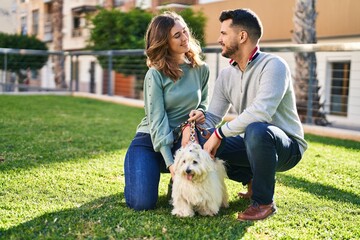 Man and woman posing with dog at park