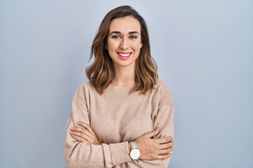 Young woman standing over isolated background happy face smiling with crossed arms looking at the camera. positive person.