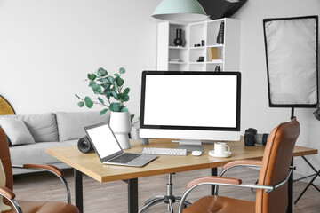 Photographer's workplace with computer, laptop and cup of coffee in studio