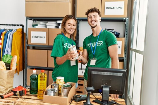 Young hispanic volunteer couple smiling happy working at charity center.